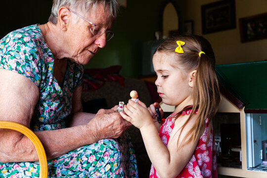 Grandmother and granddaughter playing with dolls at home
