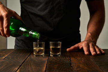 Man at a bar drinking alcohol in shot glasses. Concept of alcoholism and drinking addiction.