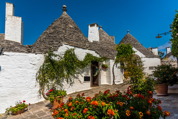 A picturesque street of traditional Trulli buildings in Alberobello, Italy decorated with summer...