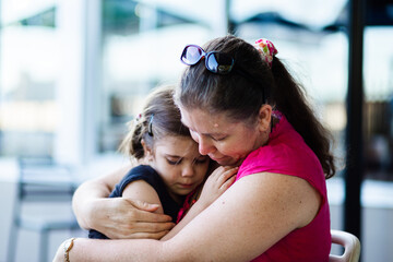 Mother comforts young daughter with close hug