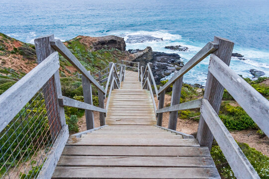 Looking down a long wooden staircase towards a rocky coastline