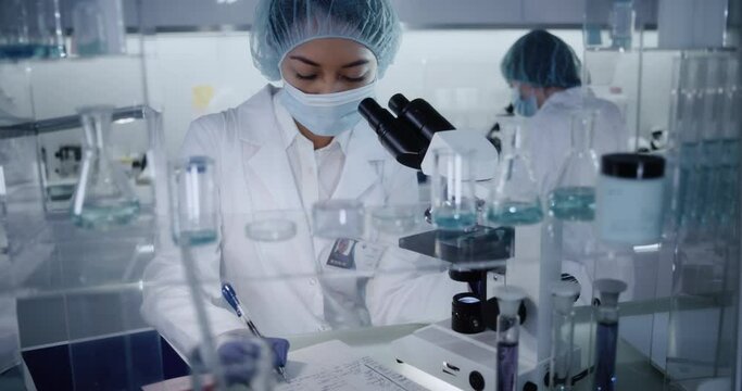 Female team working in modern laboratory. Studying genetic material with microscope. 
