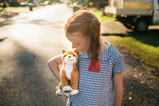 Girl in uniform cuddling her toy dog on street