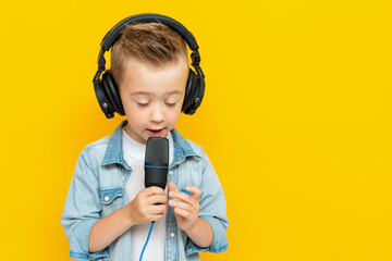 Portrait of singing little boy with headphones and microphone