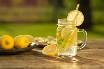 Homemade lemonade with lemon and mint in mason jar on wooden table. Refreshing summer drink. Drink making ingredients for lemonade.