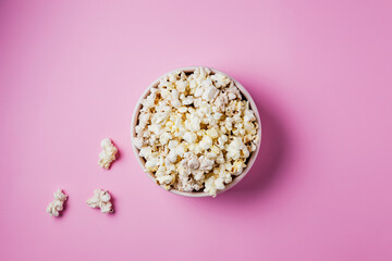 Fototapeta na wymiar A pink bowl of popcorn on pink background, top view