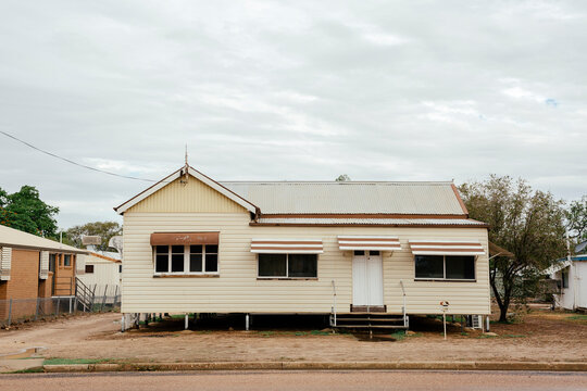 Front-on view of cream coloured Queenslander Home with brown trimming