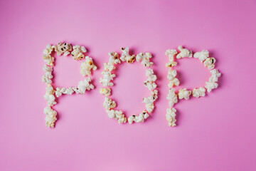 Word POP written with popcorn on pink background