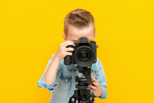 Adorable little kid taking a photo using a digital camera on a tripod