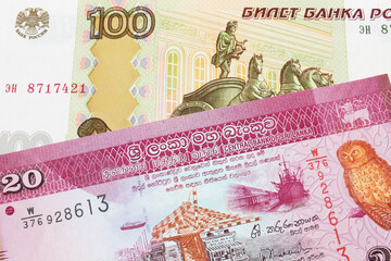 A macro image of a Russian one hundred ruble note paired up with a pink and white twenty rupee bank note from Sri Lanka.  Shot close up in macro.