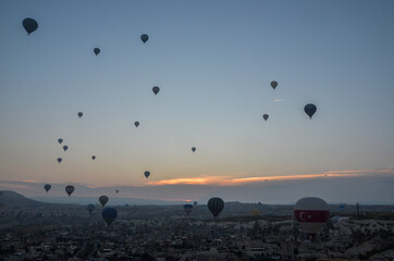 Colorful hot air balloons flying over the valley and rock formations with fairy chimneys near Goreme, Cappadocia, Turkey