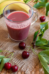 cherry banana smoothie with fresh fruit on a rustic burlap background 