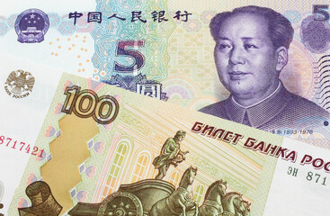 A macro image of a Russian one hundred ruble note paired up with a purple, blue and white five yuan...