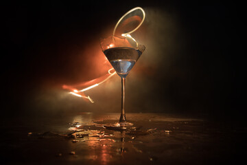 Broken glasses on wooden table at dark toned background with fog. Selective focus