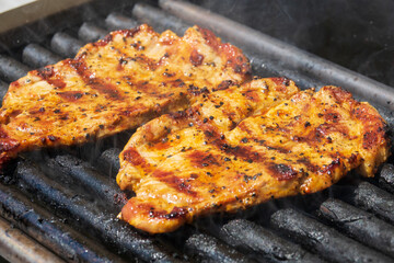 Grilling pork steaks. Delicious juicy meat steaks cooking on the grill.