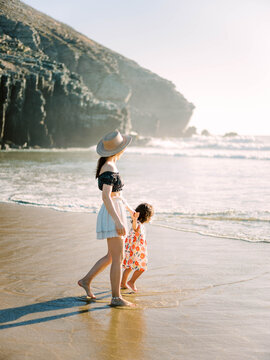 Mom And Child Walking Together On Beach