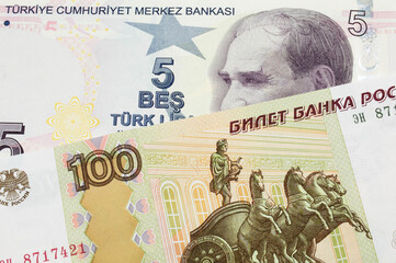 A macro image of a Russian one hundred ruble note paired up with a purple, five real bank note from Turkey.  Shot close up in macro.