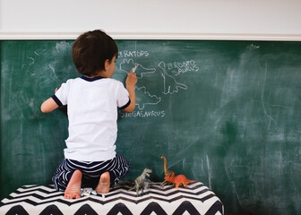 boy traces dinosaurs on chalkboard