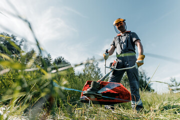 male gardener mows the grass with a lawn mower