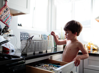 little boy puts silverware away
