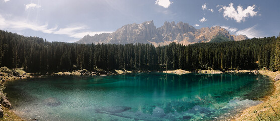 Panoramic view on incredible emerald mountain lake framed by spruce forest and dolomite mountains