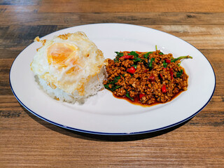 Thai food Pad ka prao with fried egg in the white dish.  Mince pork with basil leaf  menu.