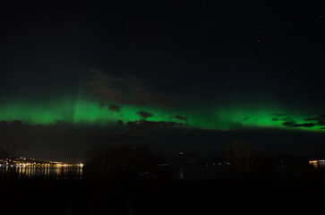 vibrant aurora borealis over silent fjord and mountain landscape