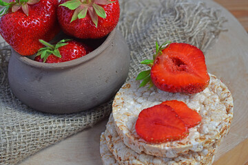 Fresh sweet strawberries in a clay pot on a wooden background.