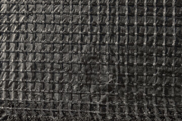 The construction of the road, laying of geomesh on soil before the asphalt pavement. Geogrid reinforcing a new roadbed, modern technologies.