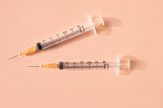Close up of syringes and sharp needles on pink background
