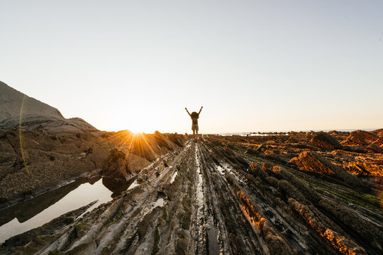 Silhouette of a girl with open arms in the Long exposure in the flysch of Zumaia