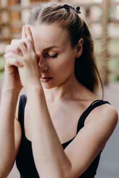 Portrait of a young caucasian woman. She closed eyes and folded palms as praying.