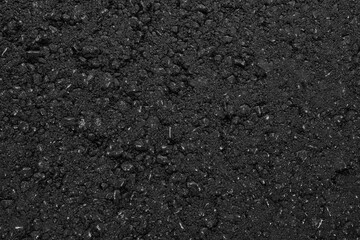 A smooth dark grey asphalt pavement texture with small rocks. Black bituminous waterproofing. Textured background.