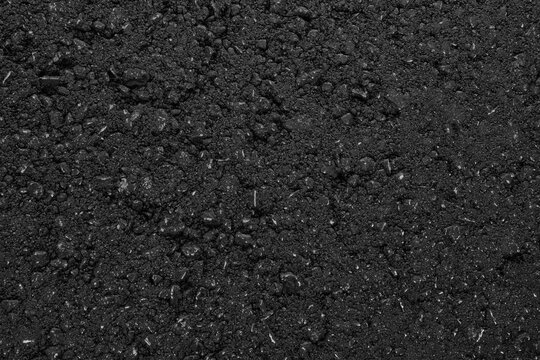 A smooth dark grey asphalt pavement texture with small rocks. Black bituminous waterproofing. Textured background.