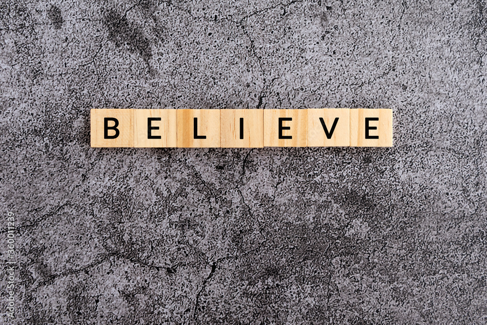 Wall mural believe text on wooden block textures background