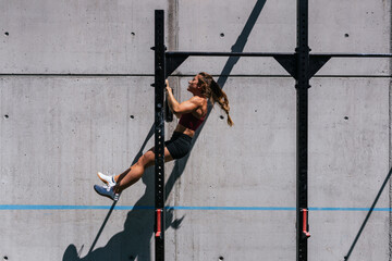 Side view sporty Woman Doing Exercises On A Horizontal Bar