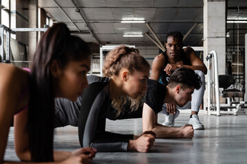 African American instructor looking at exercising athletes