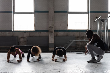 Fitness trainer controlling athletes in gym