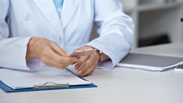 cropped view of doctor giving blister pack with pills to patient