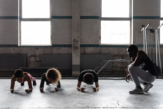 Fitness trainer controlling athletes in gym