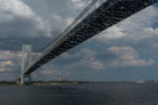 View from under a bridge through the water splashed and worn windows of a ferry boat.