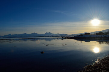 sun over blue fjord landscape