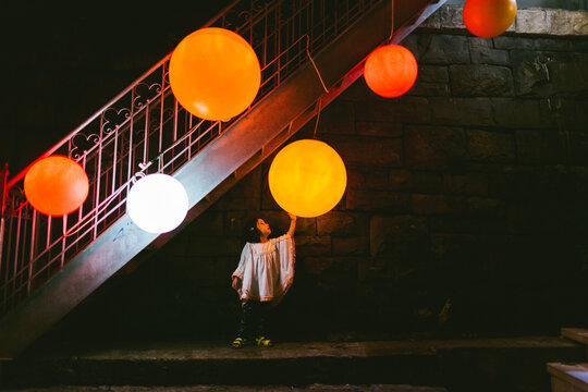 Fototapeta Scene of a kid under the stairs touching a big orange lamp