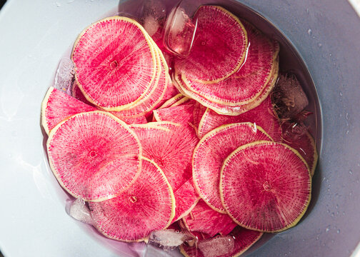 Sliced pink watermelon radishes in ice water