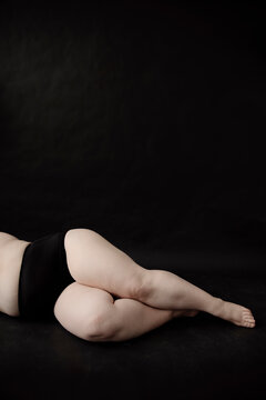 Crop of legs of woman with overweight on black background.