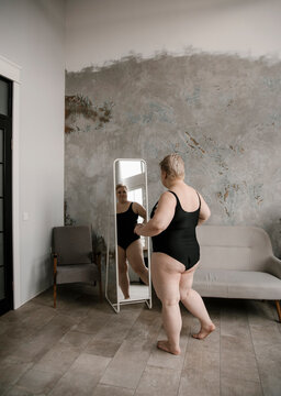 Huge blonde woman looking at reflection in mirror.