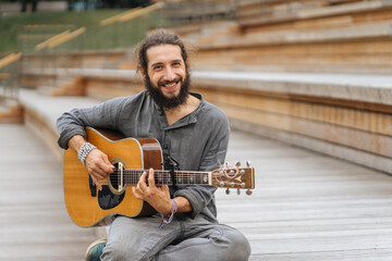bearded young man playing guitar in a park
