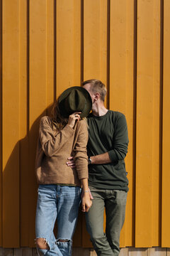 Couple kissing covering faces with hat
