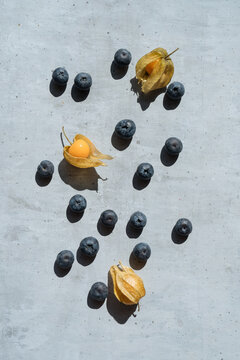 Blue berries and physalis on grey surface