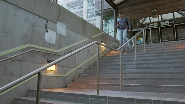 High quality 4k video of a young man who climbs the stairs at the station and holds a phone in his hands and a backpack on his back. A man hurries on a train, bus, airplane subway, transport 